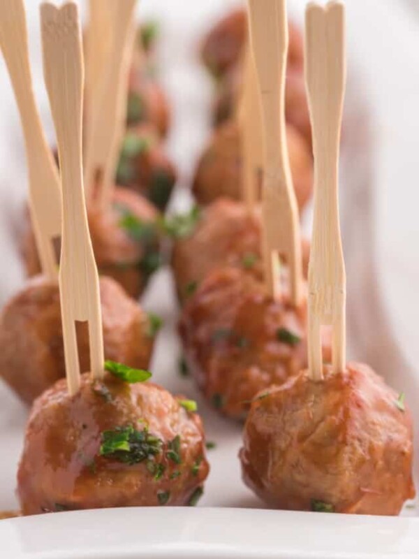 Meatballs on toothpicks on a white plate.