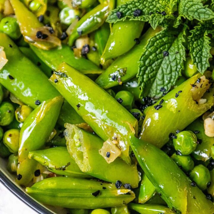 english peas and snap peas sautéed with mint and garlic in a white bowl