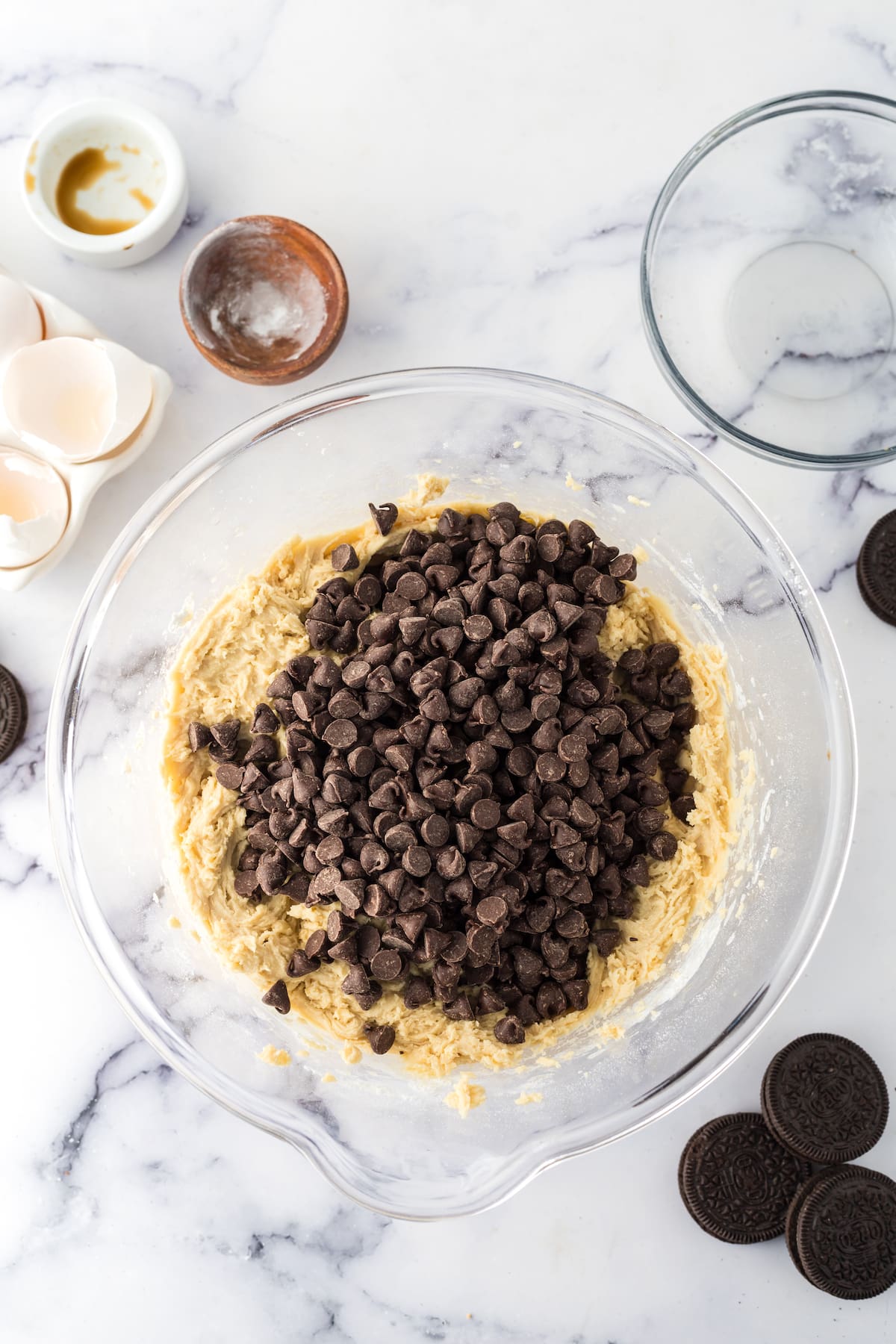 Oreo cookie dough in a bowl with eggs and chocolate chips, perfect for making easy cookie bars or oreo stuffed cookies.