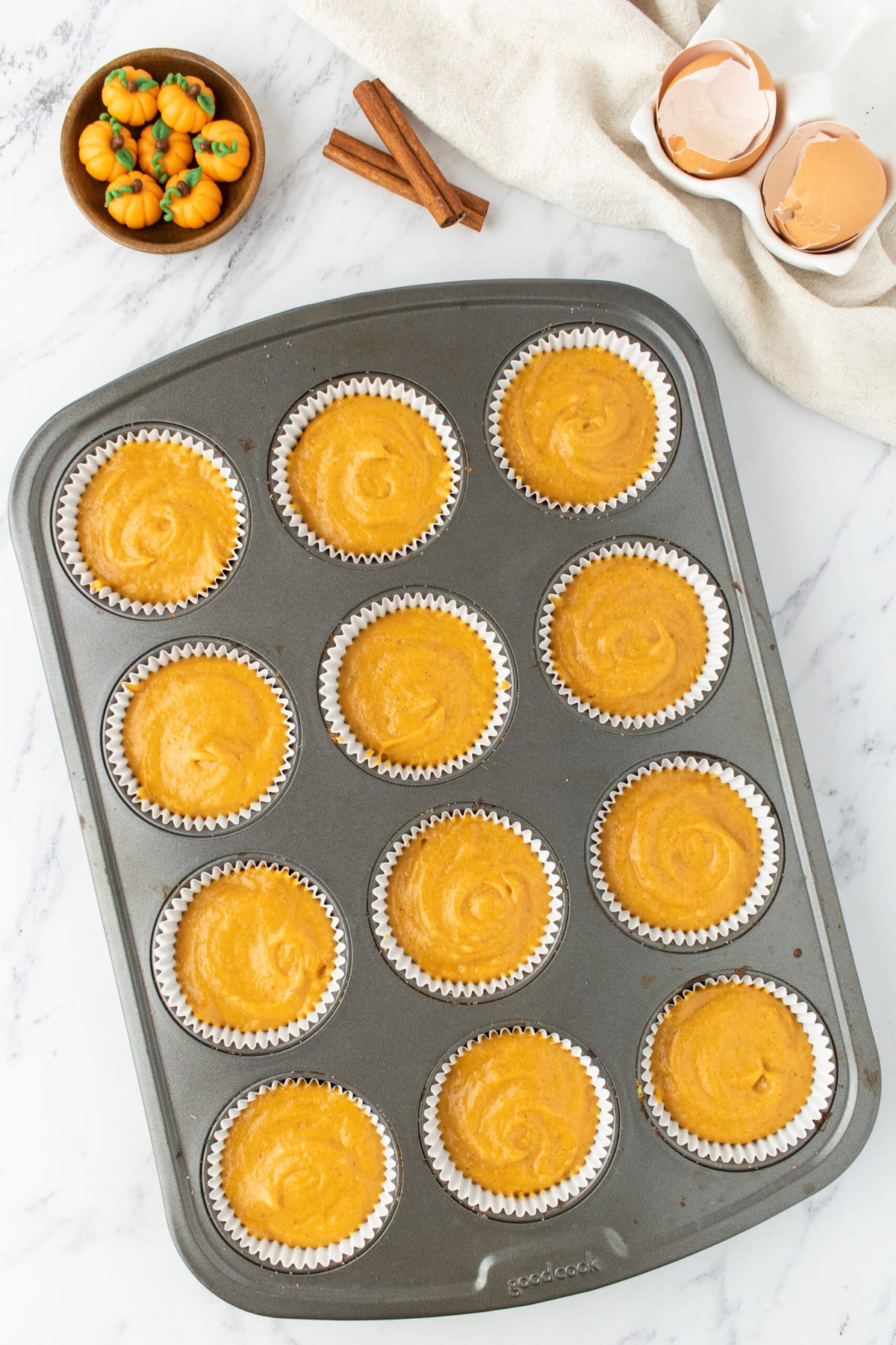 pumpkin cupcake batter in cupcake liners in a muffin tin