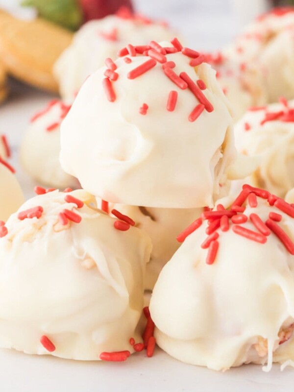 a stack of strawberry shortcake truffles dipped in white chocolate with pink sprinkles on top