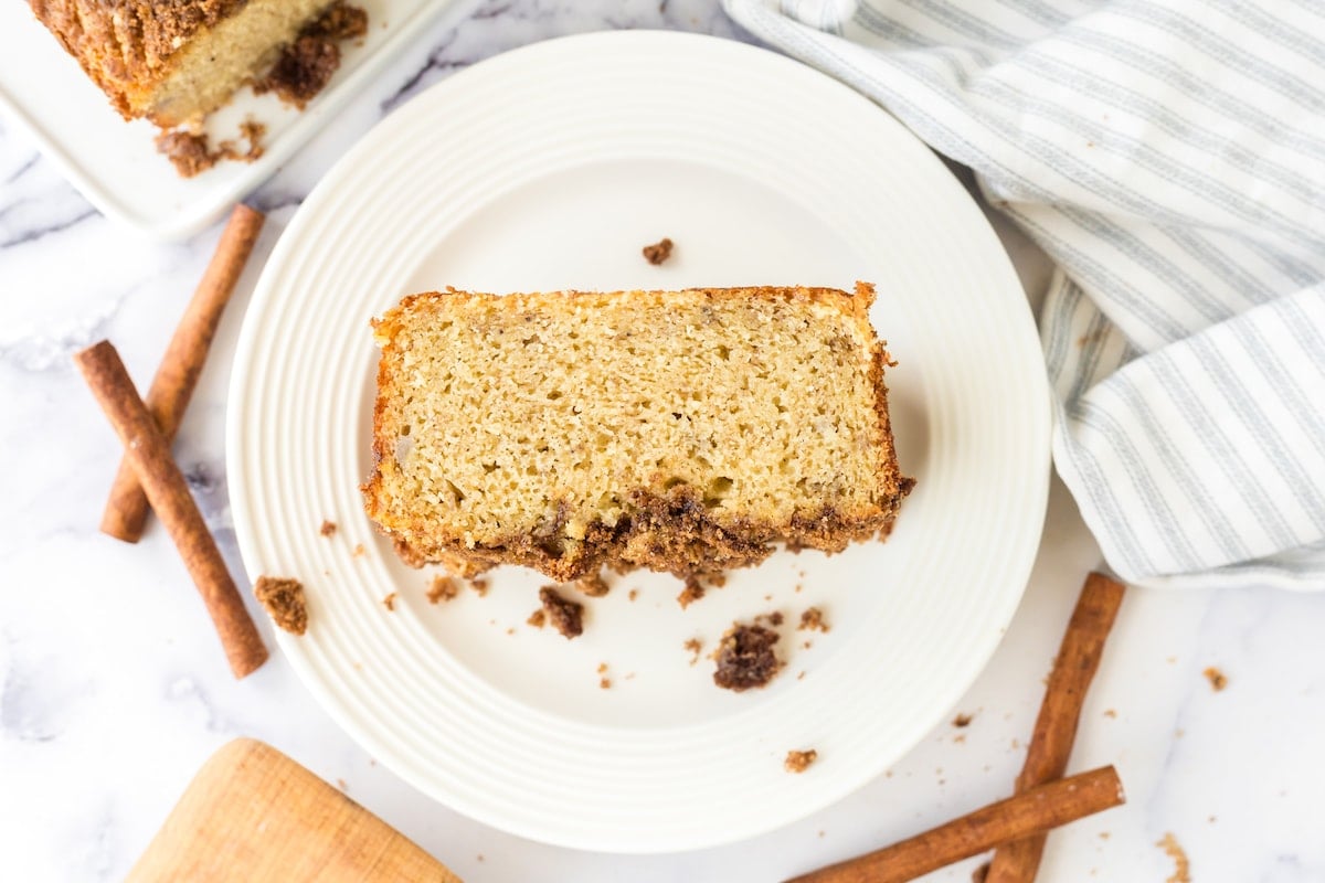 a slice of banana bread with cinnamon crumble topping on a white plate