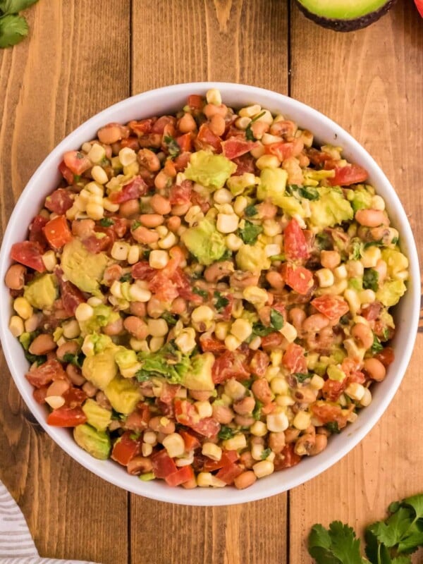 cowboy caviar with corn, beans, avocado, tomatoes, cilantro in a bowl on a table