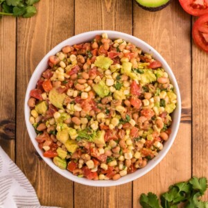 cowboy caviar with corn, beans, avocado, tomatoes, cilantro in a bowl on a table
