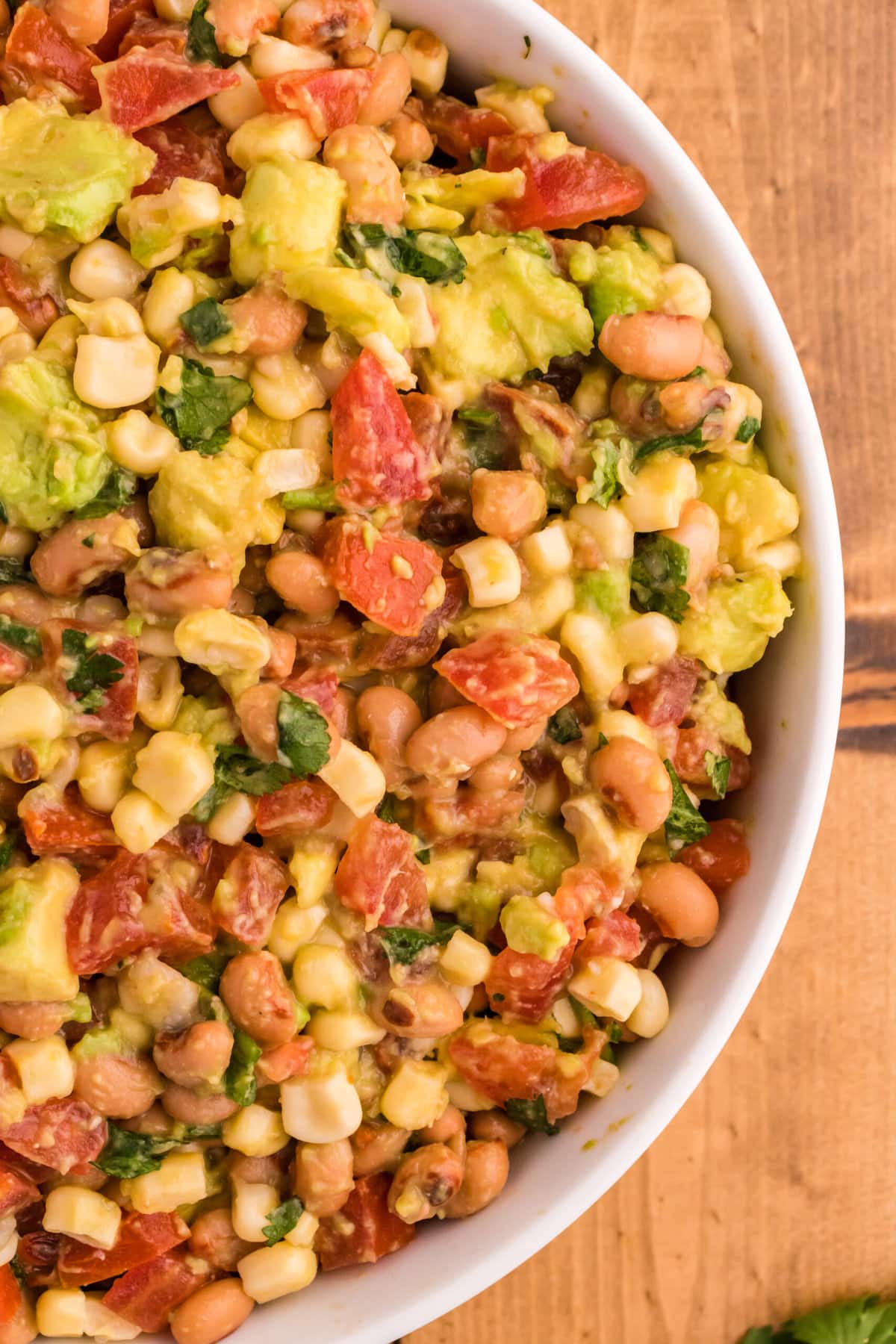 cowboy caviar with corn, beans, avocado, tomatoes, cilantro in a bowl on a table