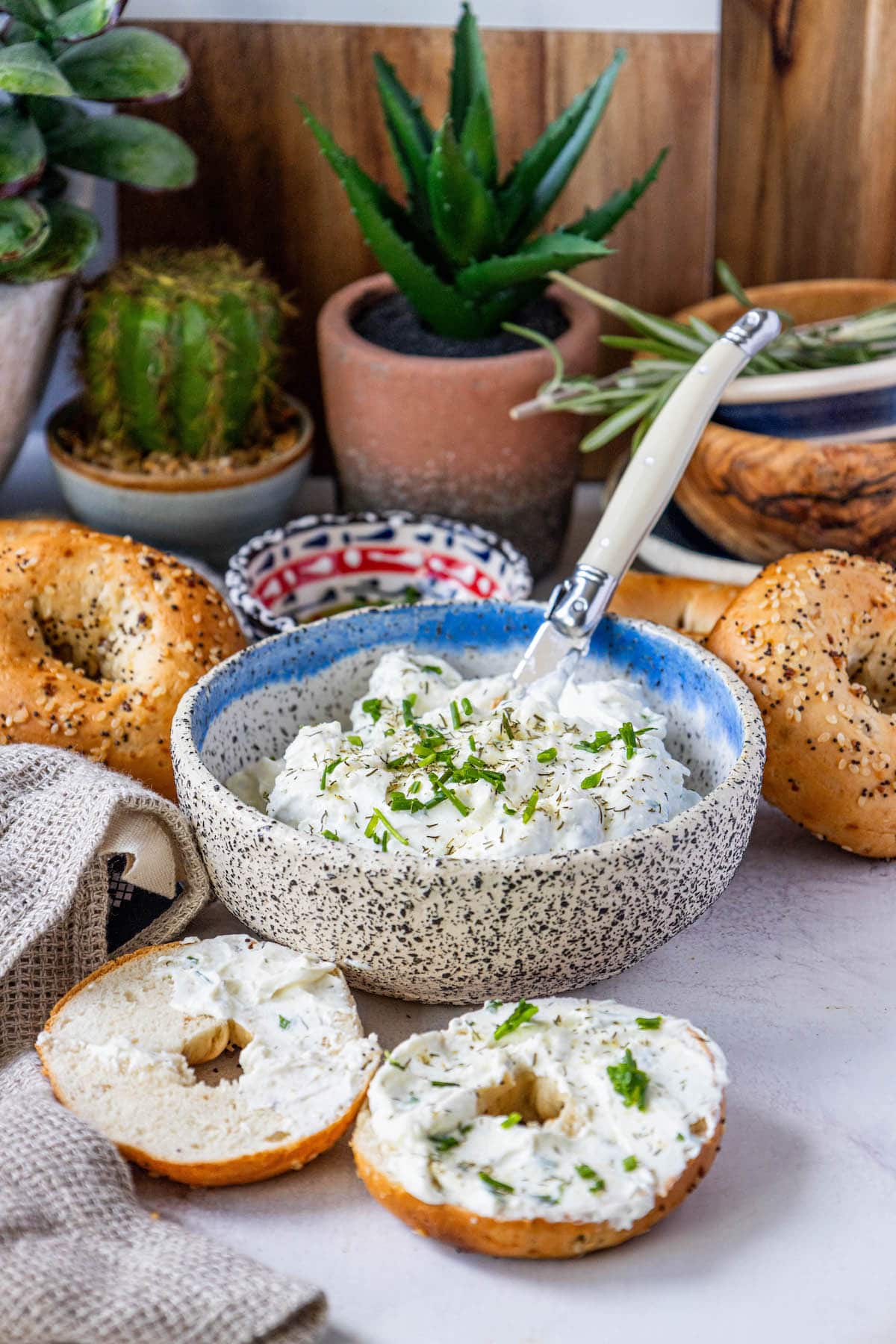 everything bagels on a table covered in dill schmear with chopped chives and pickle seasoning sprinkled on top