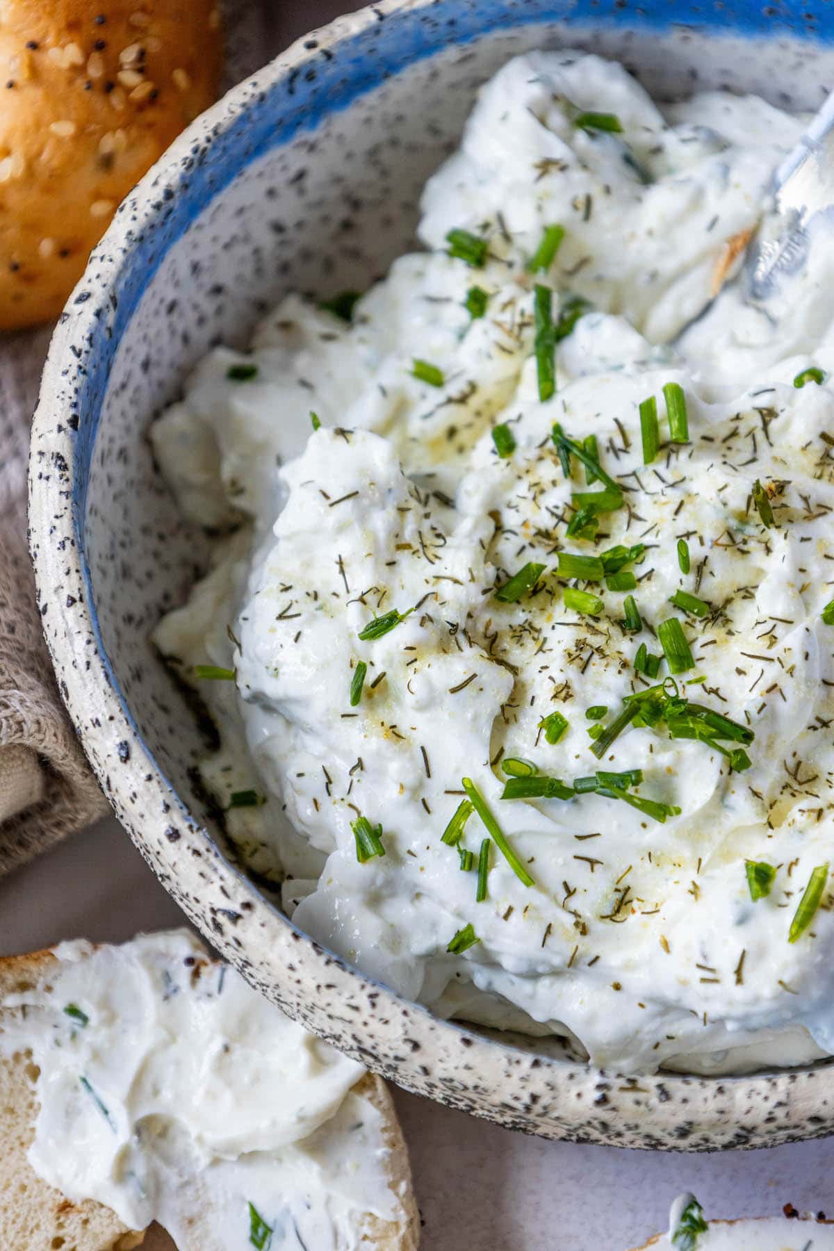 everything bagels on a table covered in dill schmear with chopped chives and pickle seasoning sprinkled on top