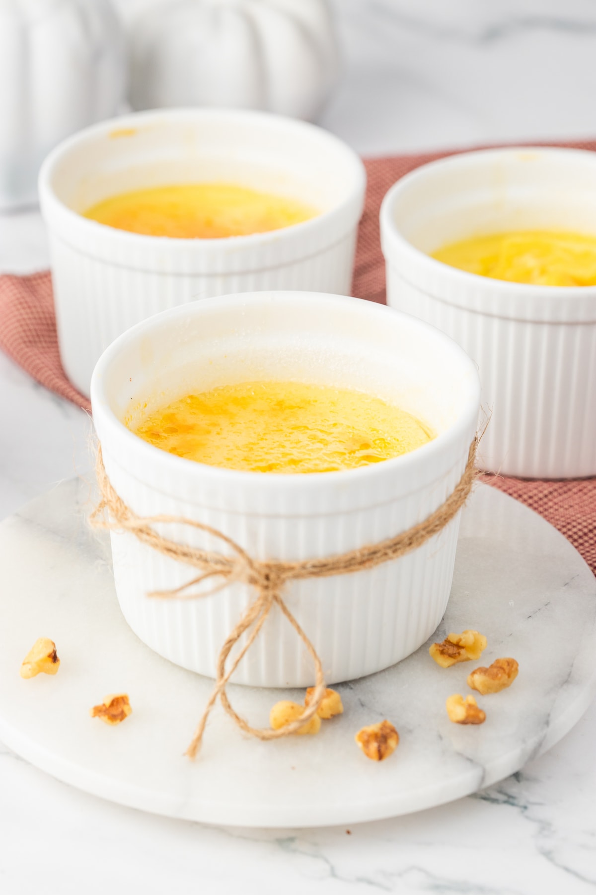 Creme Brûlée in small white ramekins with a twine rope tied around the cups. 