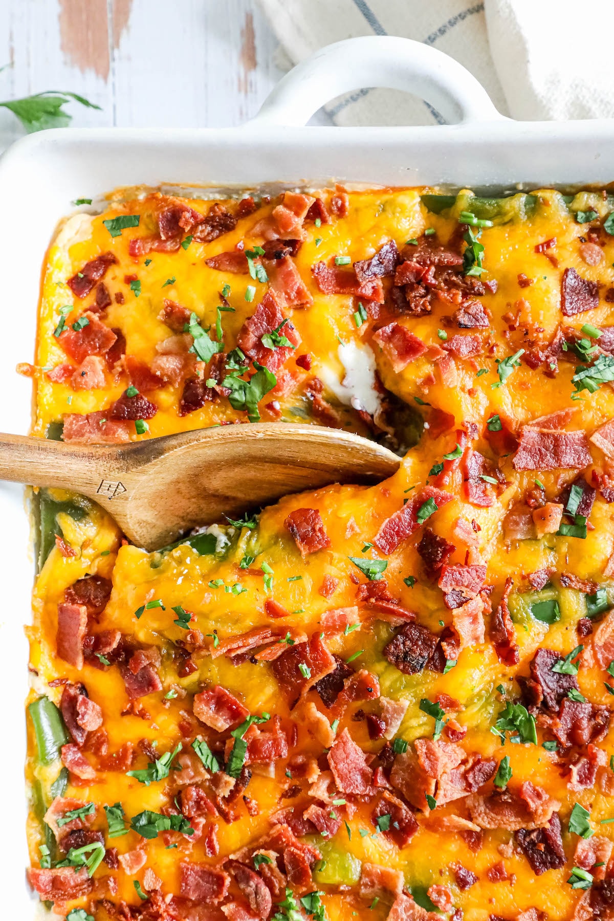 a spoon digging in to cheesy bacon topped chicken and jalapeño popper casserole