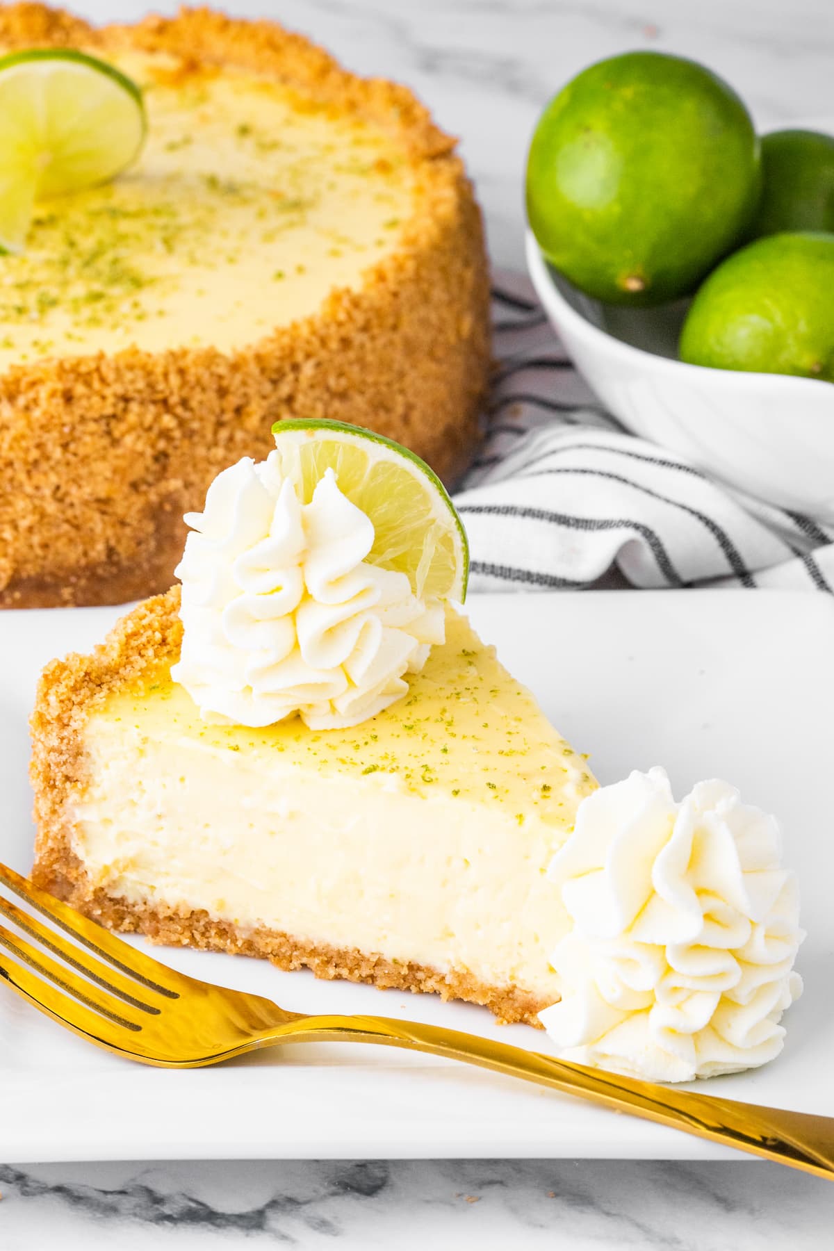 slices of key lime cheesecake on a white plate with whipped cream dollop and a slice of key lime on top