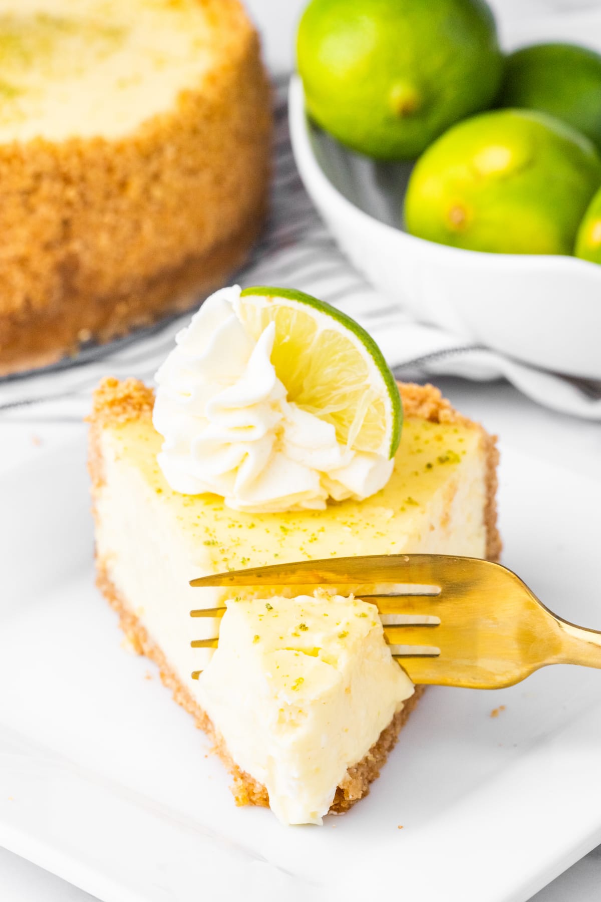 a fork cutting into a slice of key lime cheesecake
