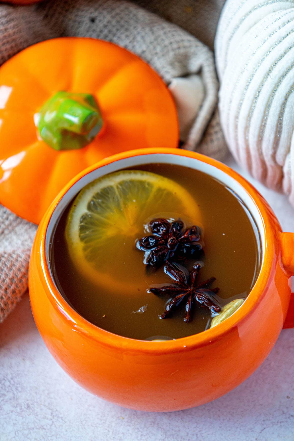 cider in a pumpkin shaped mug with a slice of lemon and star of anise