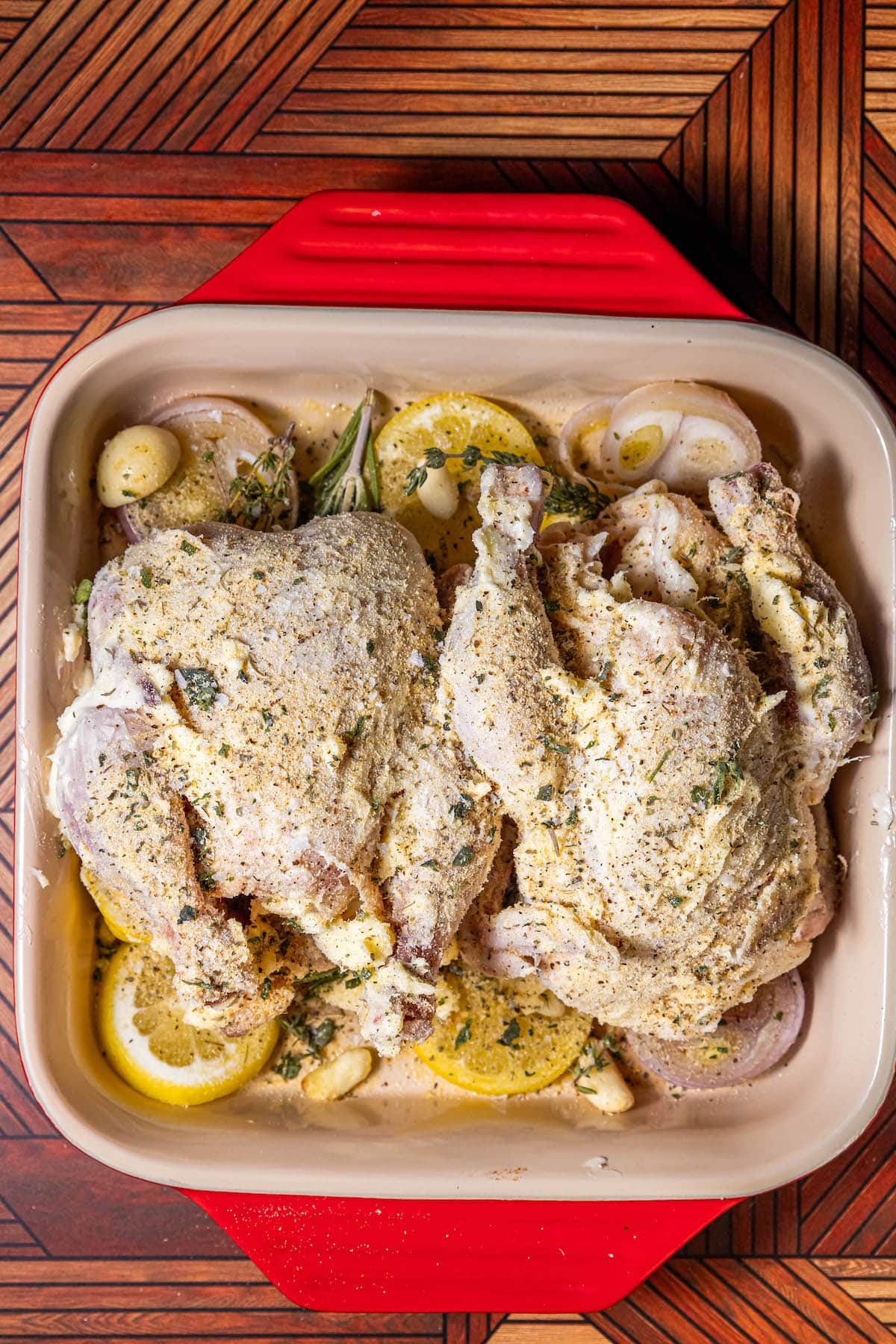 A red baking dish with easy roasted Cornish game hens and lemons in it.