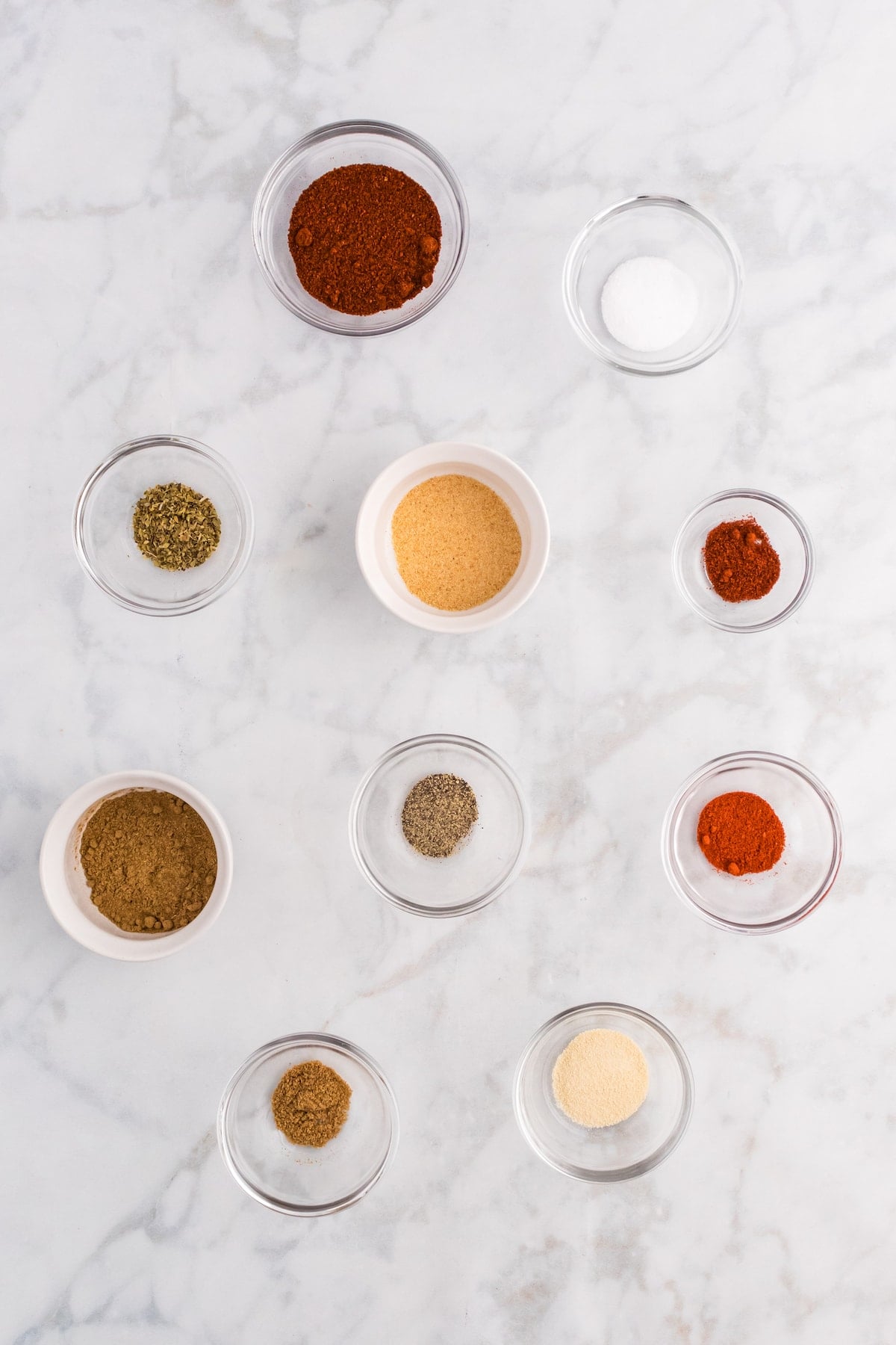 herbs and seasonings in small bowls on a table