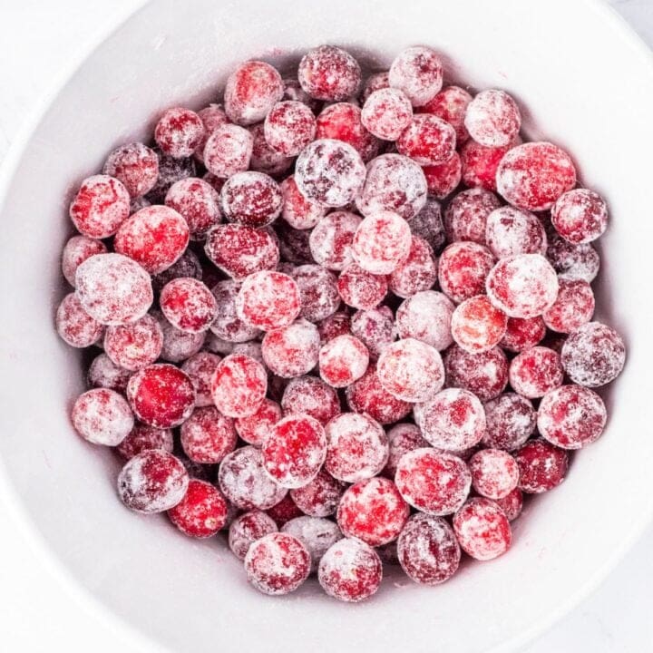 Frozen candied cranberries in a white bowl.