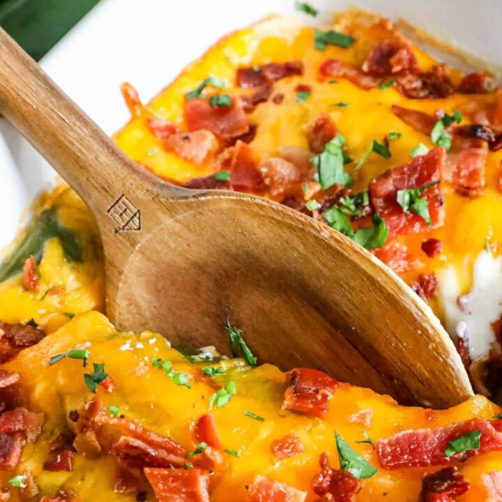 a spoon digging in to cheesy bacon topped chicken and jalapeño popper casserole