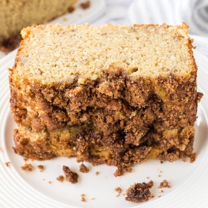 slices of banana bread with cinnamon crumble topping stacked on a white plate