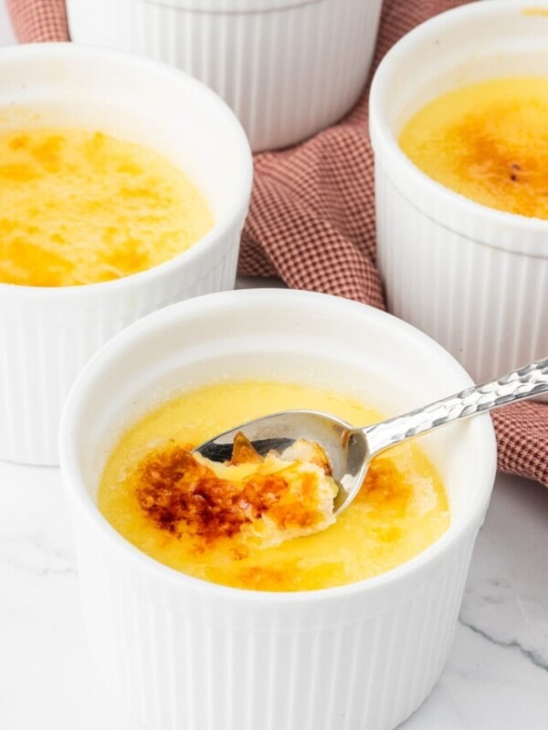 Three bowls of creme brulee with a spoon.