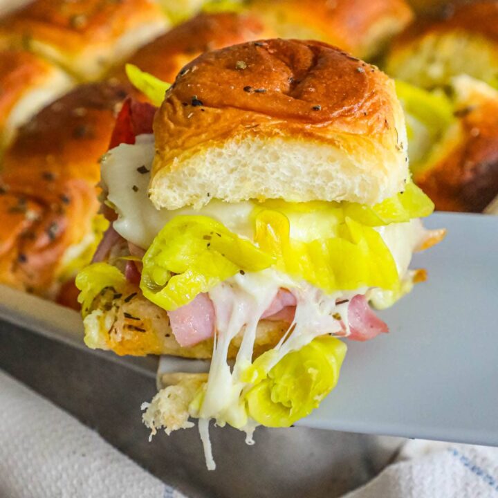 Hot ham and cheese Italian sliders in a pan.