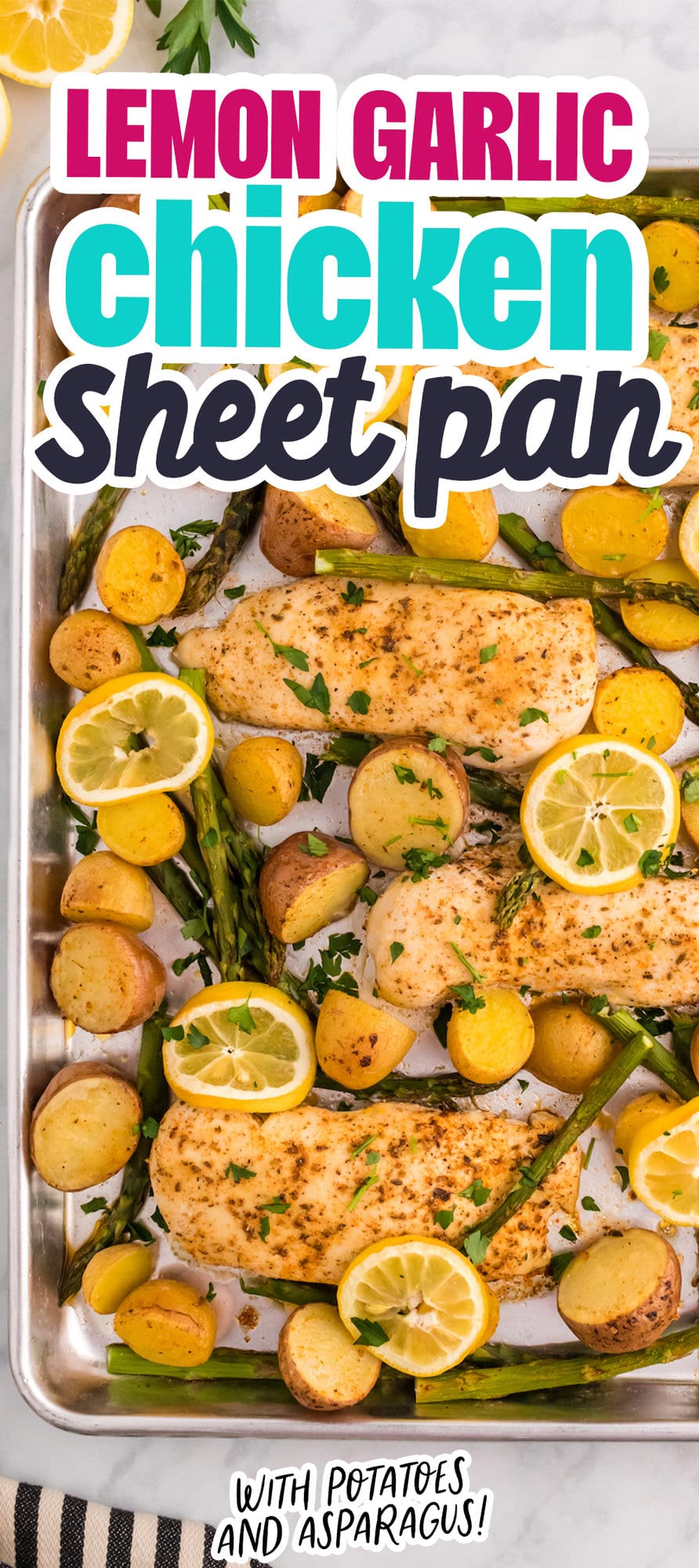 baked chicken breasts, lemon slices potatoes, and asparagus on a baking sheet