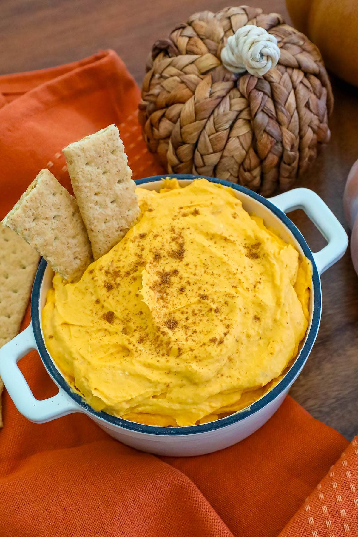 A bowl of pumpkin fluff dip accompanied by crackers on a napkin.