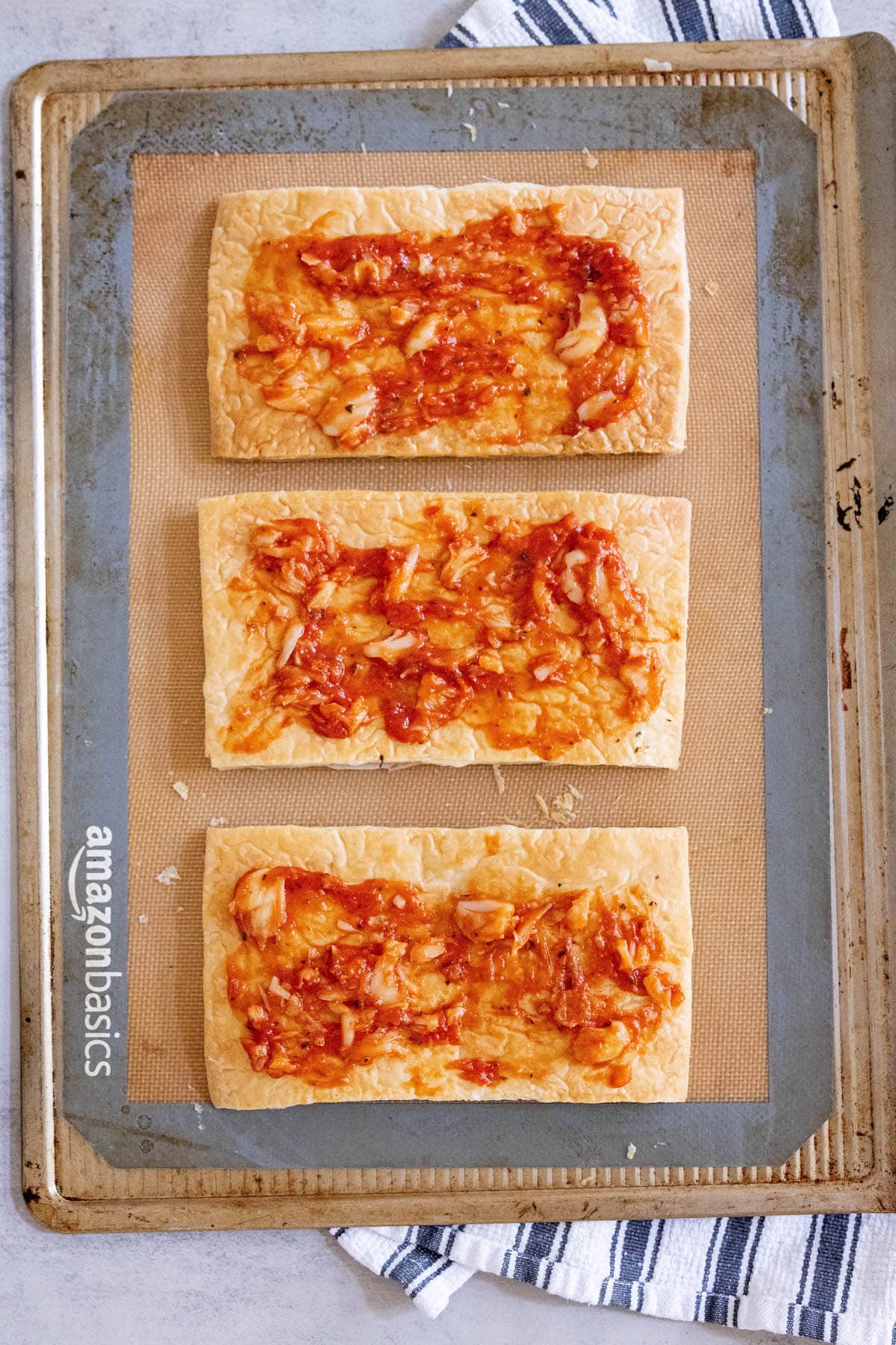 puff pastry with tomato sauce on a baking sheet
