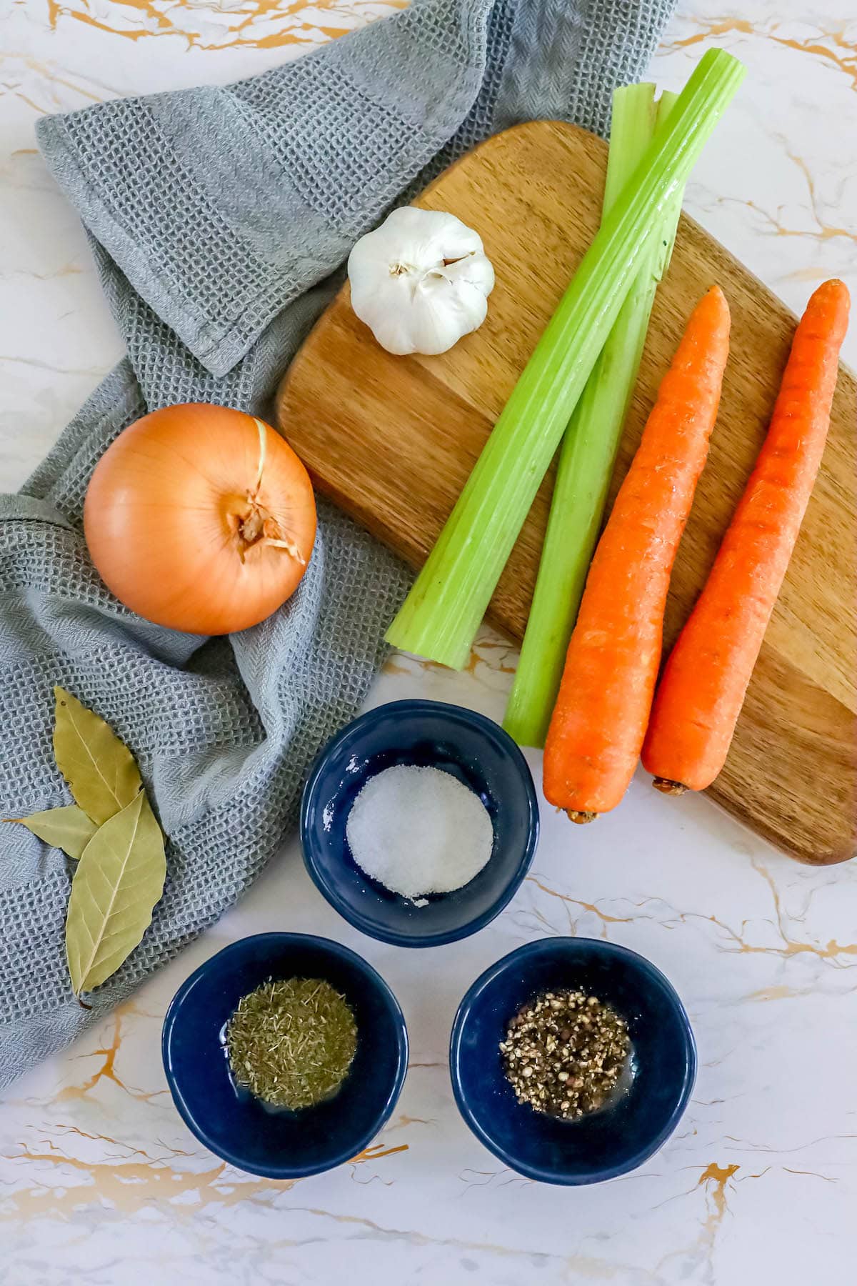 carrots, onion, garlic, bay leaf, spices, and salt set out