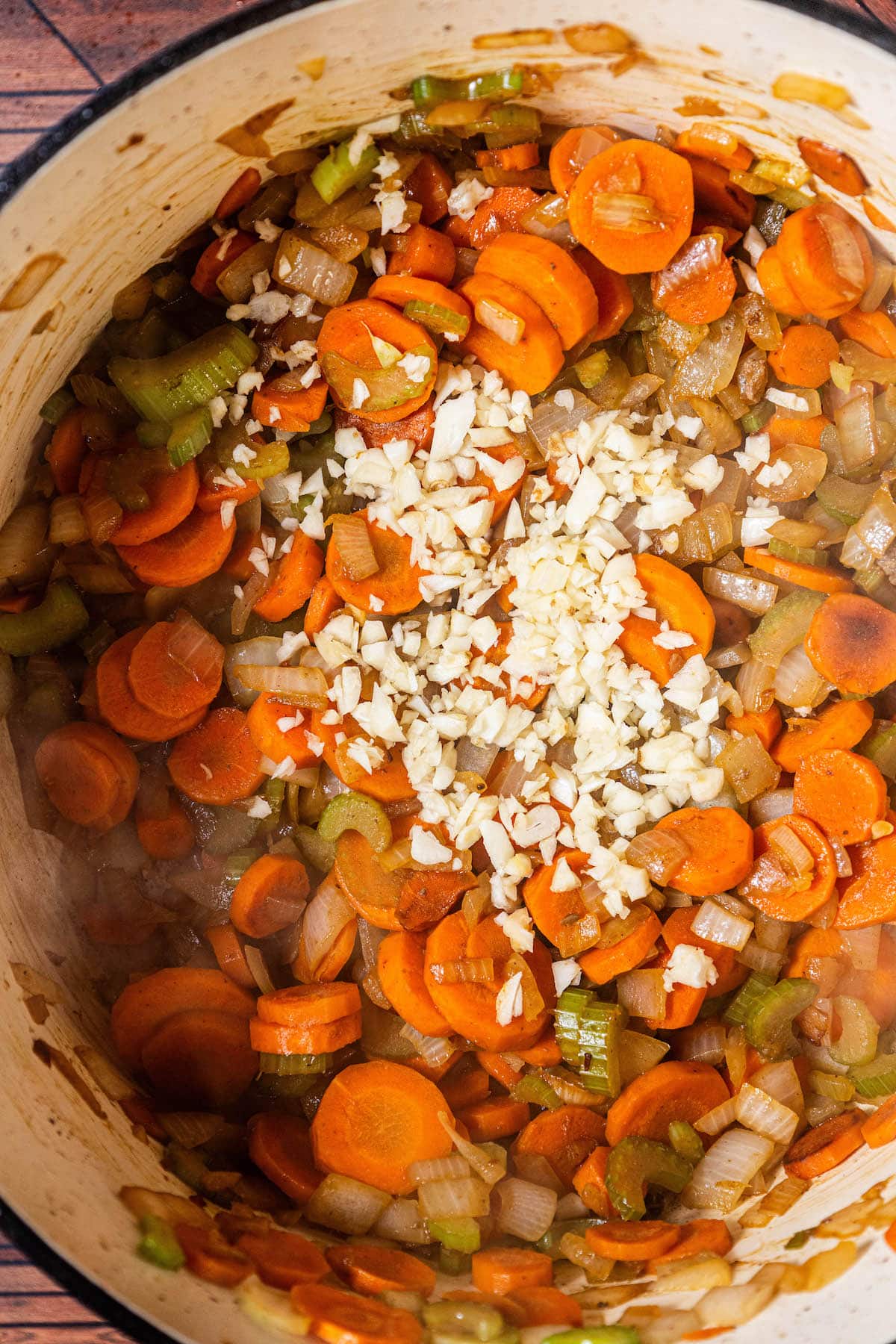 carrots, celery, and onion, in a pot with garlic on it