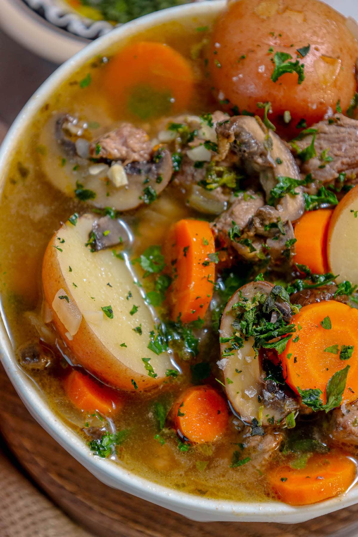 stew meat, carrots, potatoes, and minced parsley in a bowl in stock