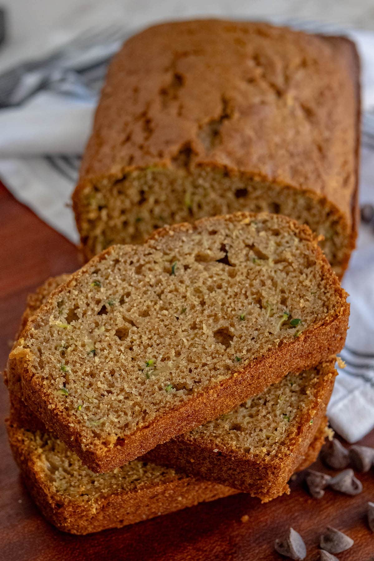 baked zucchini bread slices stacked on top of each other on a cutting board