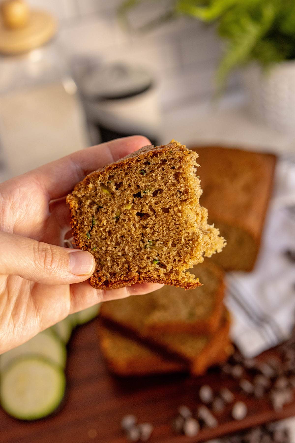 a hand holding a piece of zucchini bread