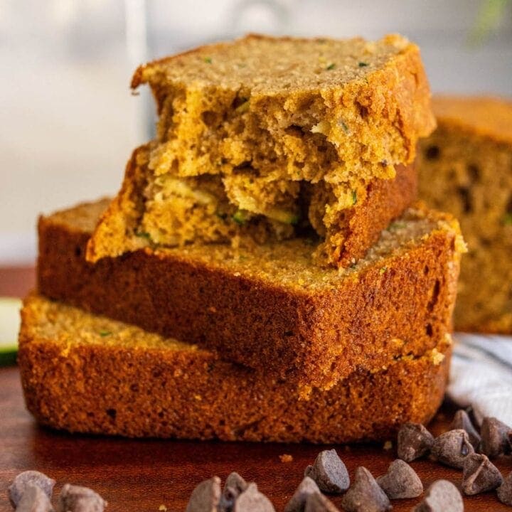 baked zucchini bread slices stacked on top of each other on a cutting board