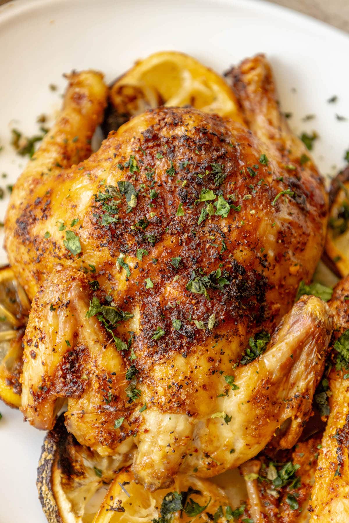 air fried cornish game hens seasoned with herbs and topped with chopped parsley on a white plate