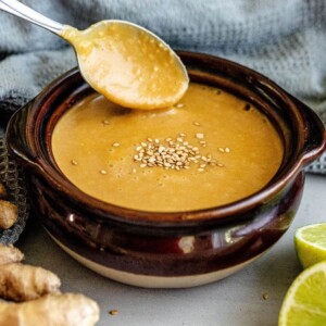 A bowl of soup with a slice of ginger, topped with miso dressing.