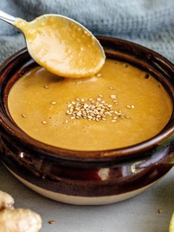 A bowl of soup with a slice of ginger, topped with miso dressing.