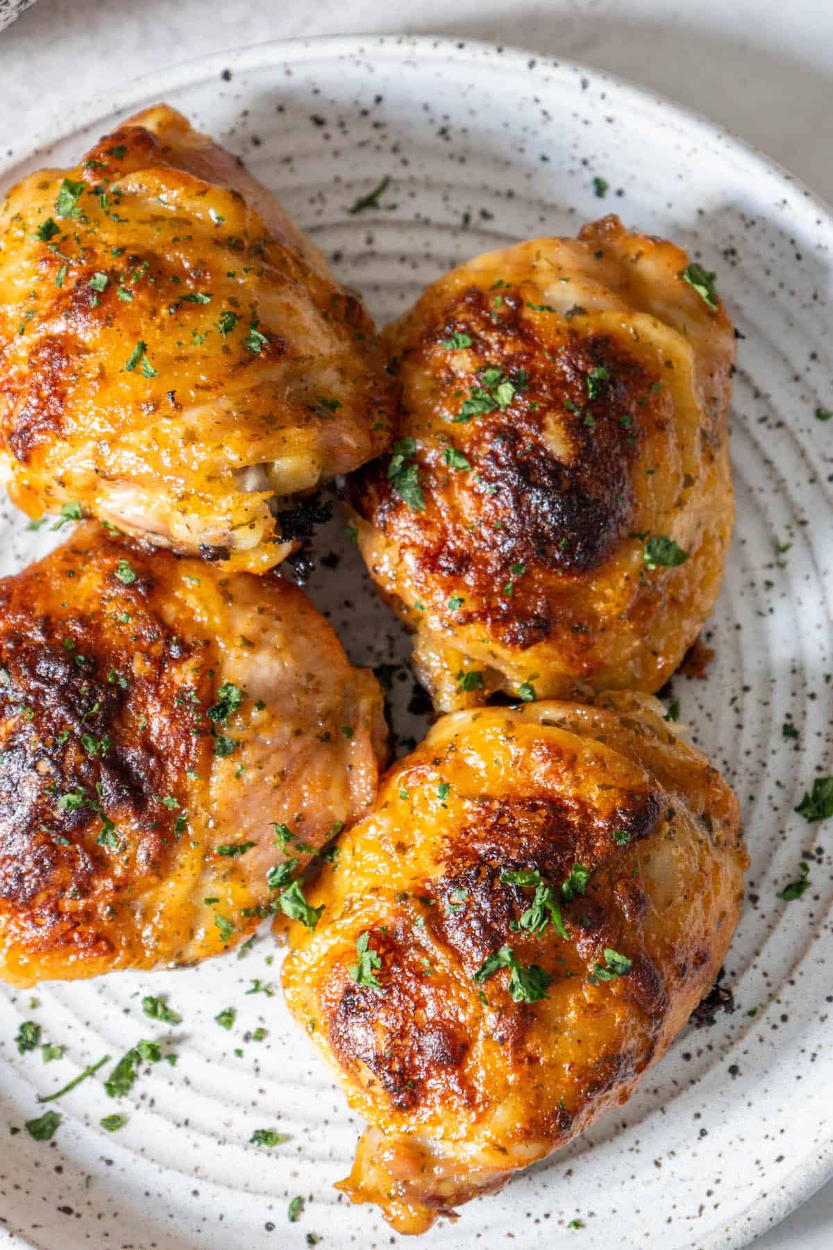 Baked ranch chicken thighs on a white plate with parsley.