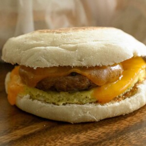 A breakfast sandwich with freezer egg muffins and cheese on a wooden table.