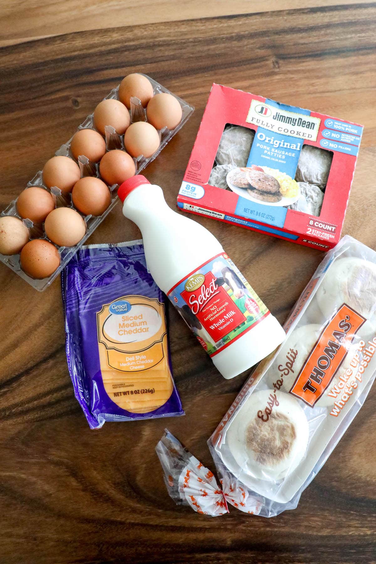 a table with english muffins, creamy, eggs, cheesy, and breakfast sausage
