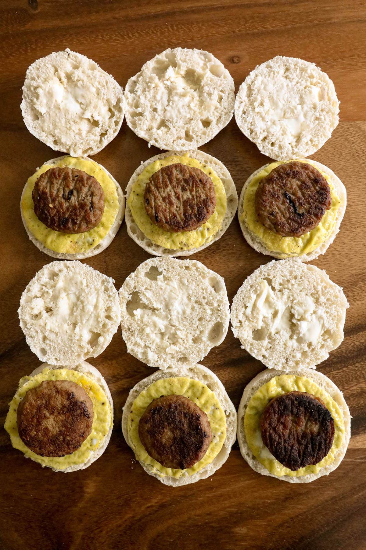 A group of freezer sausage egg breakfast sandwiches on a wooden table.