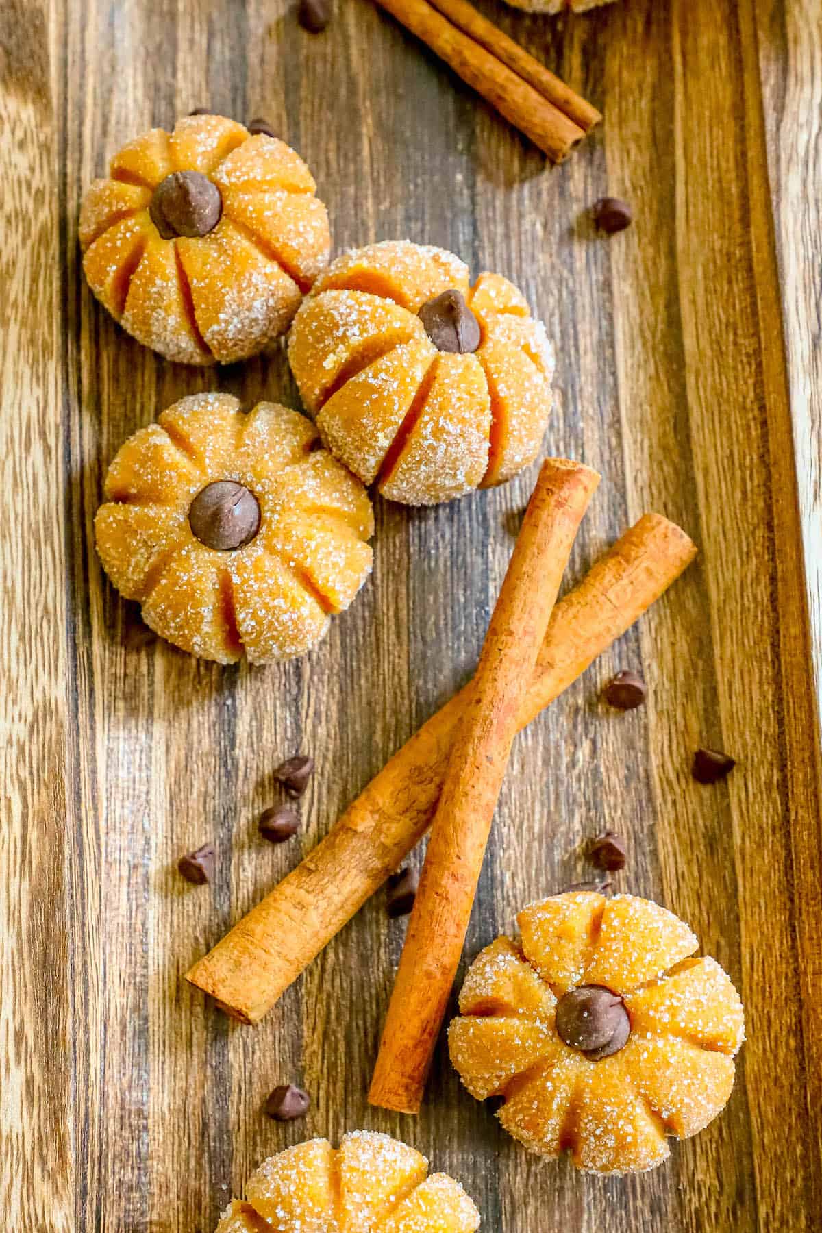 Pumpkin spice cookies on a wooden cutting board with pumpkin cheesecake truffles.