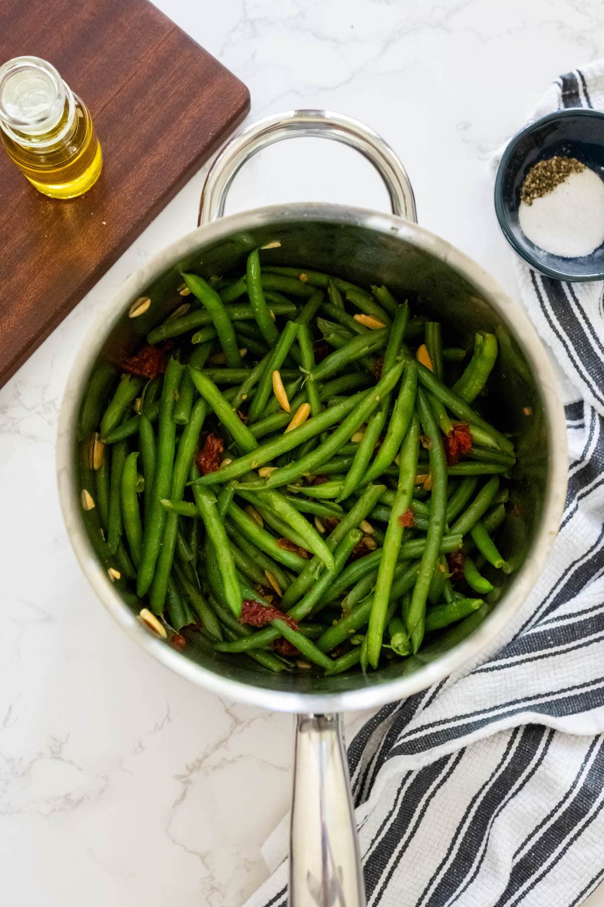 Cheesy green beans in a pan on a white table.