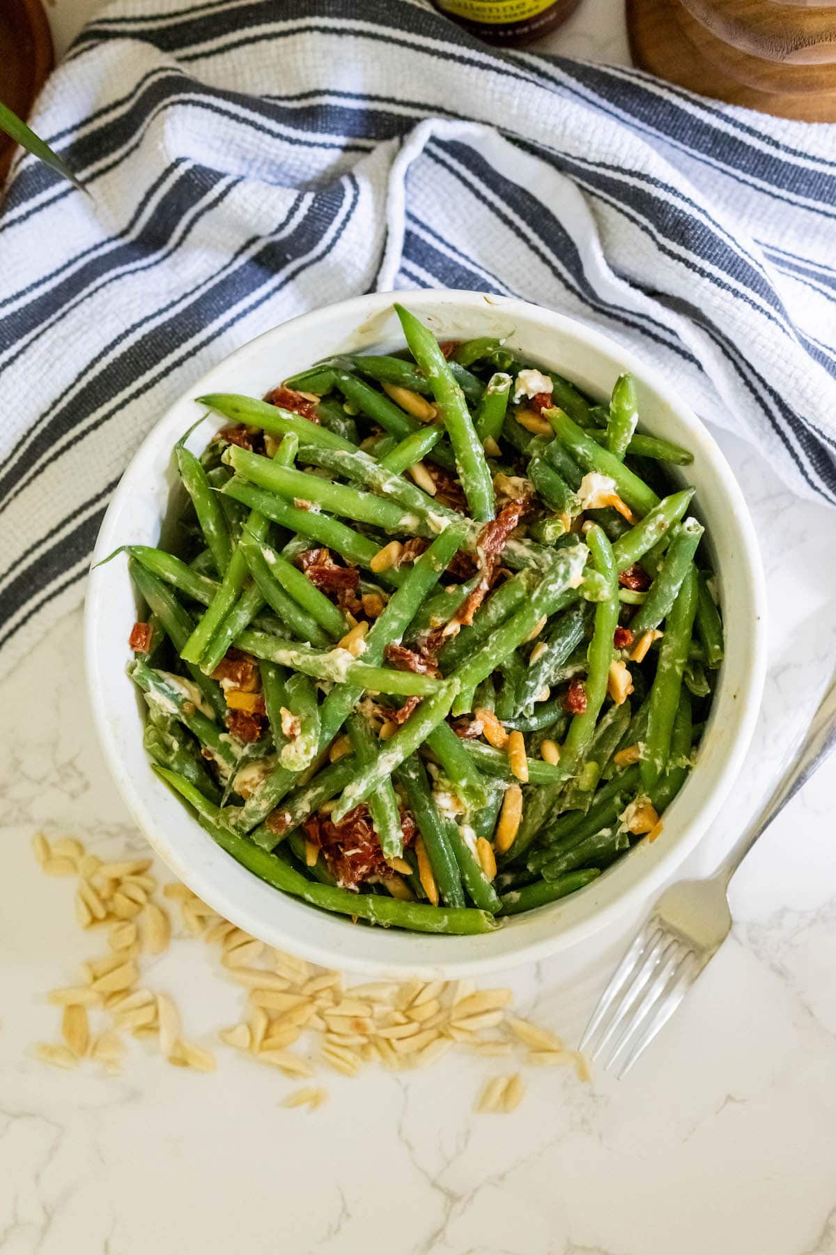 Green bean salad with cheesy sun-dried tomato, slivered almonds around the bottom