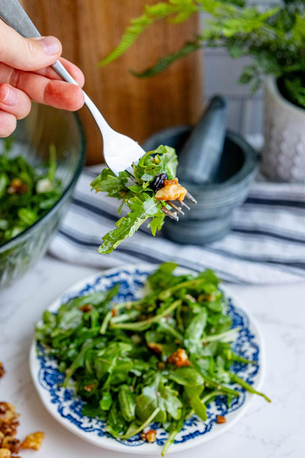 A person is holding a fork over a plate of Arugula Salad.