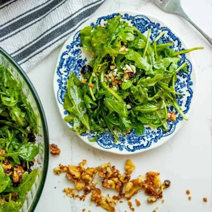 A bowl of arugula salad with walnuts.