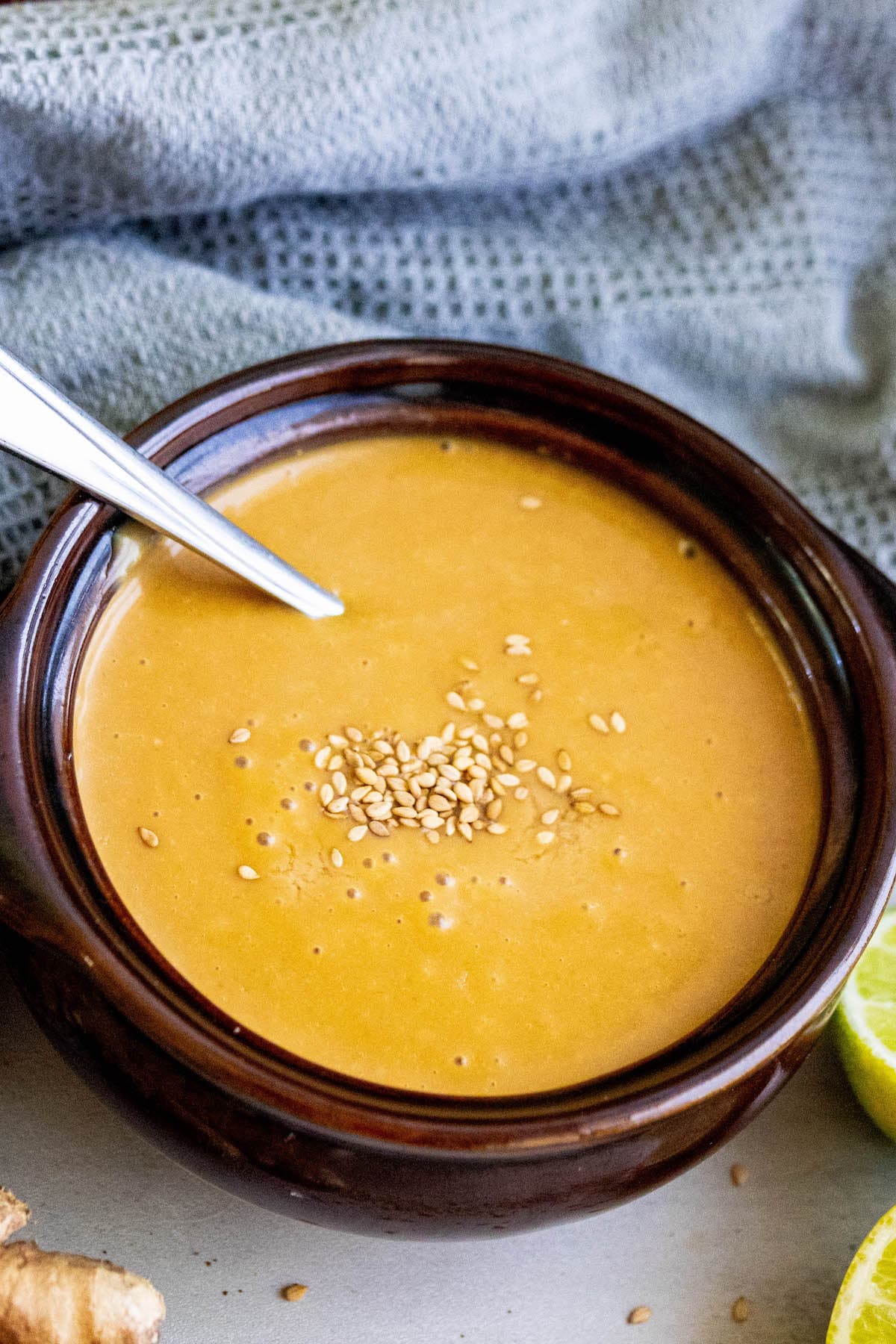 creamy dressing with sesame seeds with limes and ginger around it