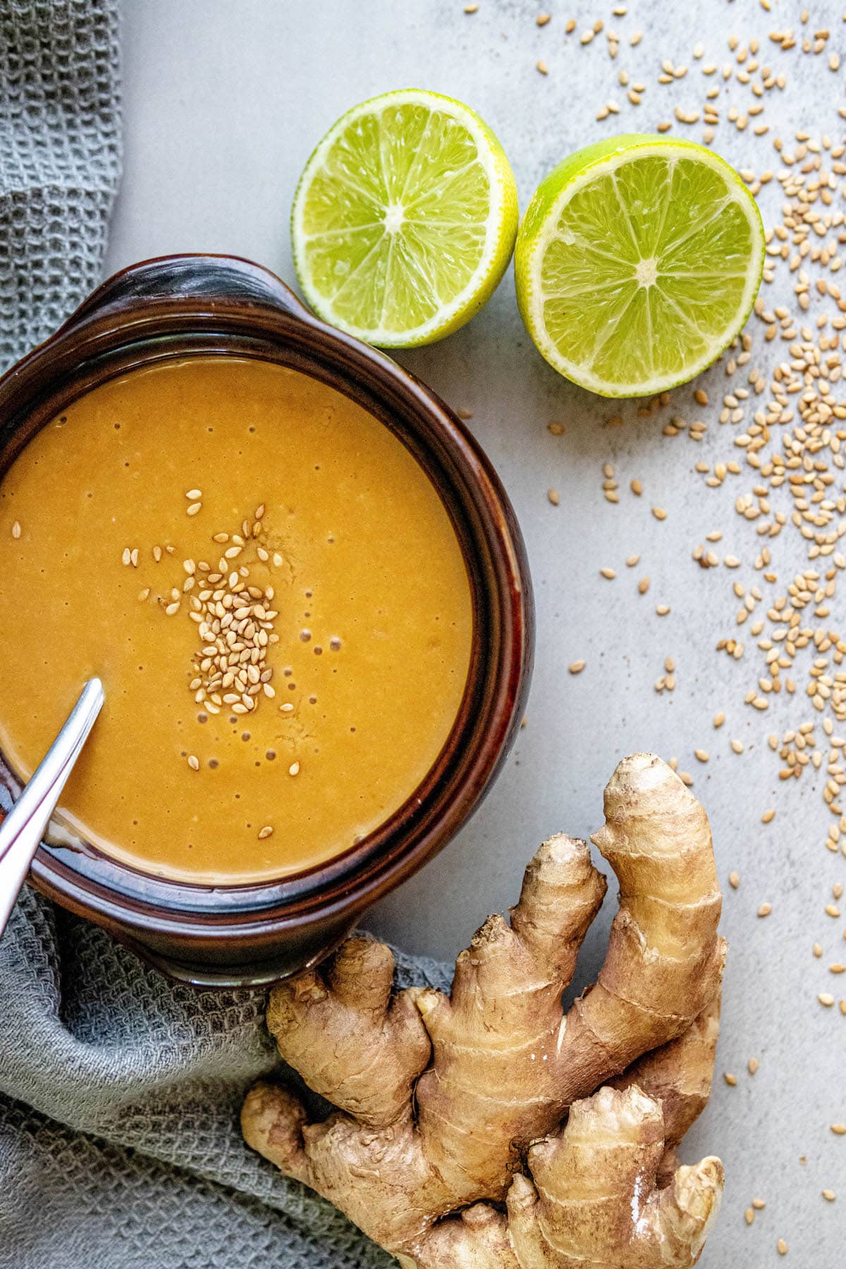 creamy dressing with sesame seeds with limes and ginger around it