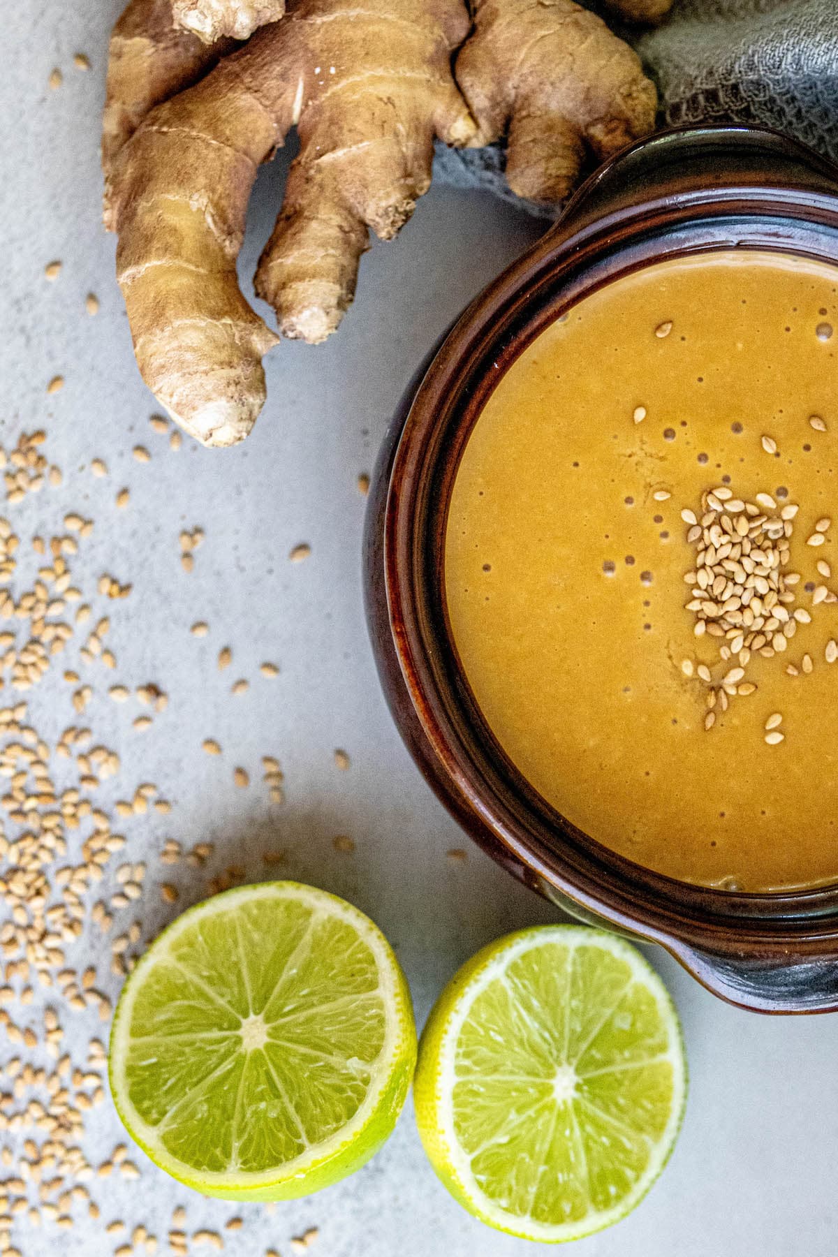 creamy dressing with sesame seeds with limes and ginger around it