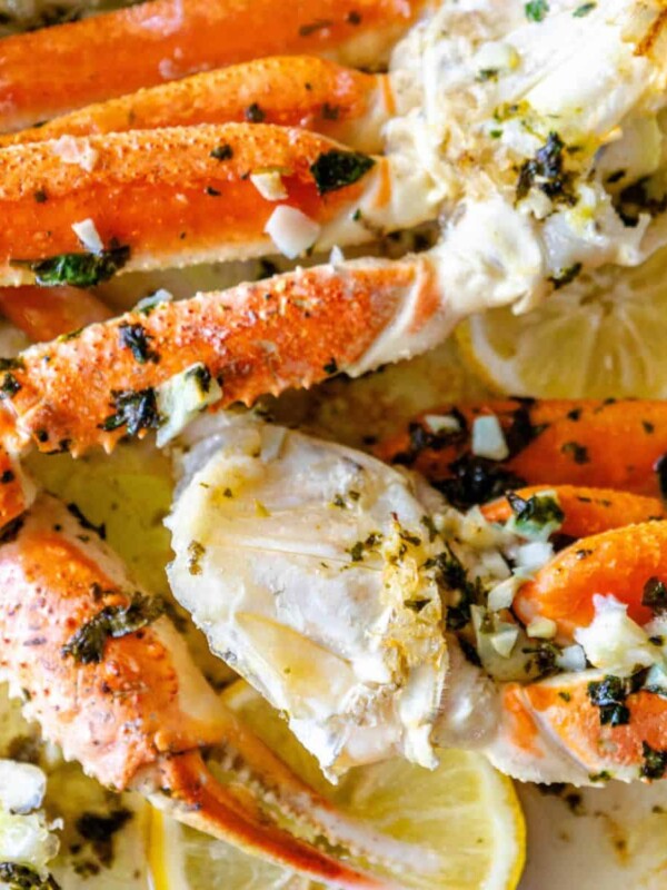 Baked Snow Crab Legs with lemon and herbs on a plate.