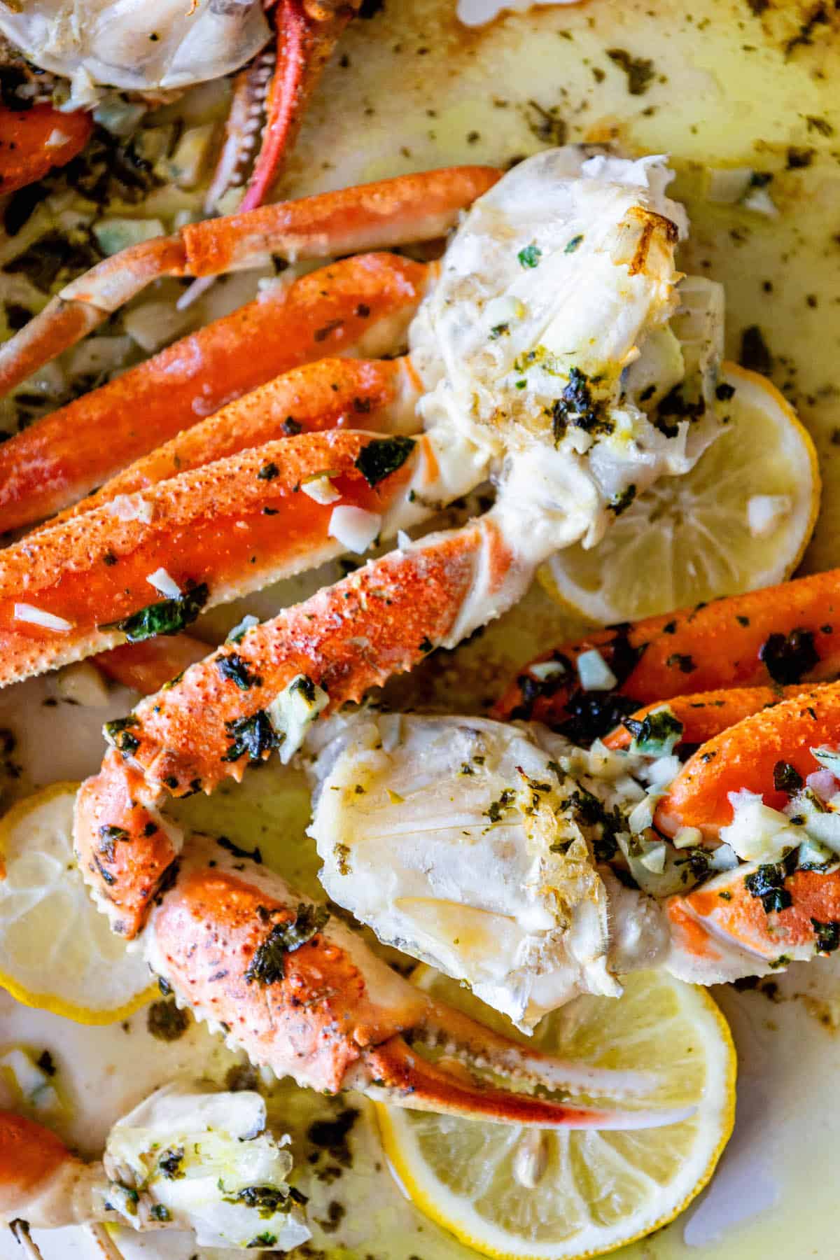 Baked Snow Crab Legs garnished with lemon and herbs.