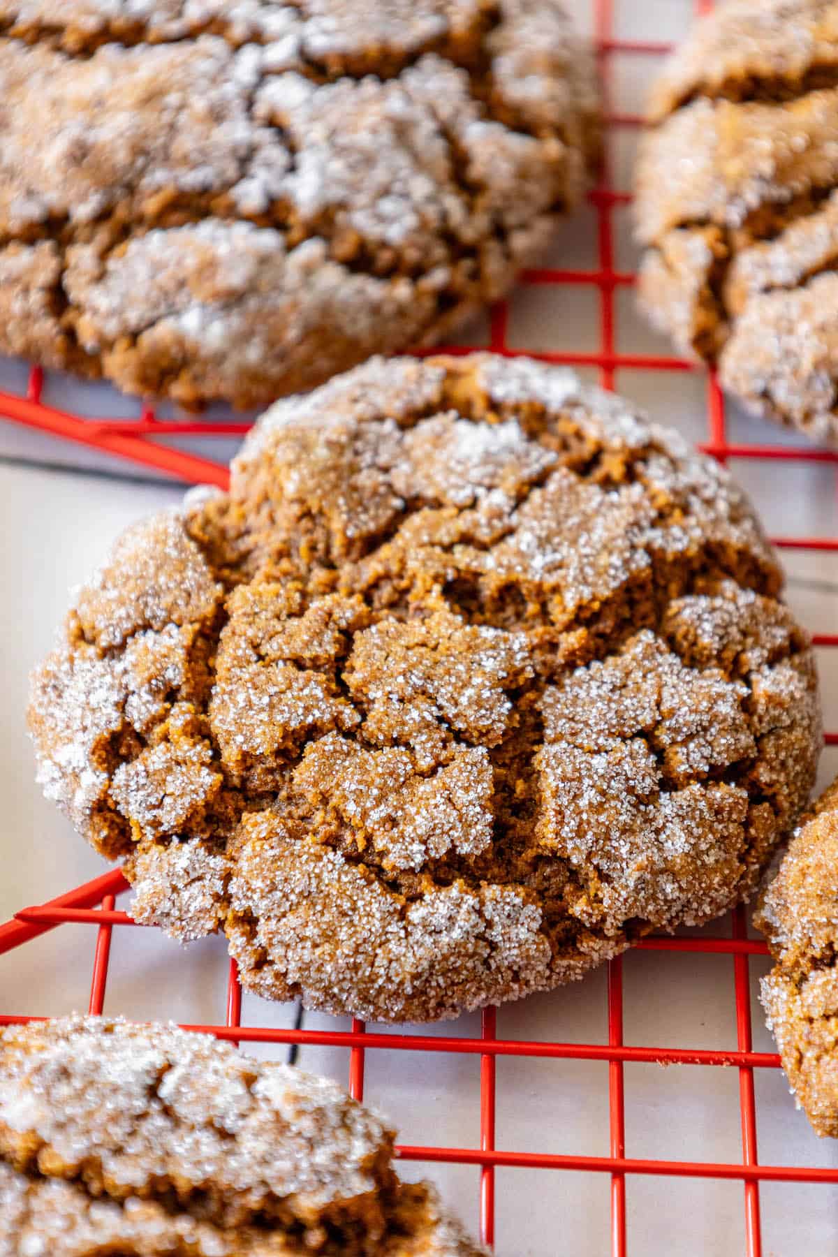 Soft gingersnap cookies recipe on a cooling rack with powdered sugar.